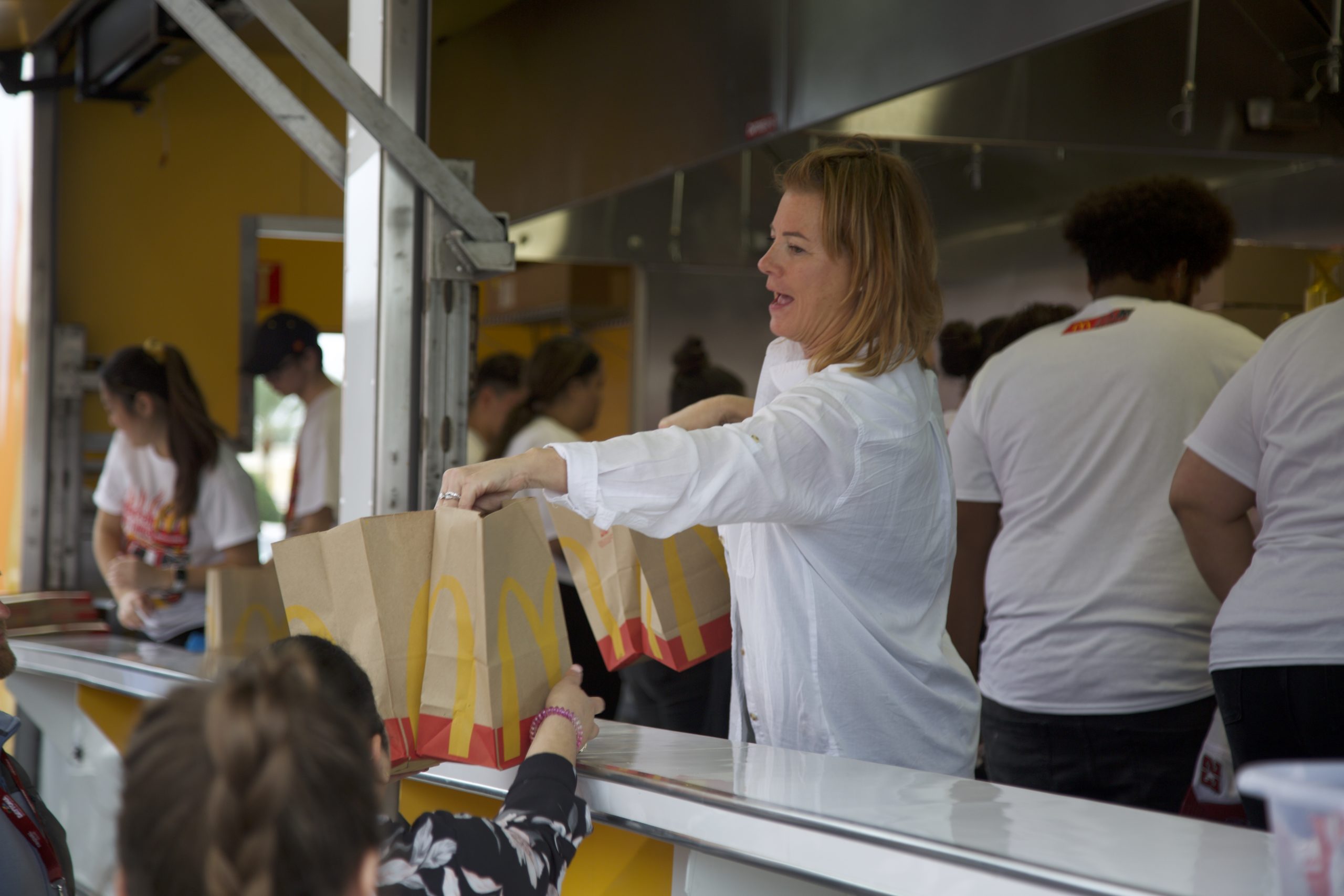 Woman in food truck passing Mc Donalds food bag to customers