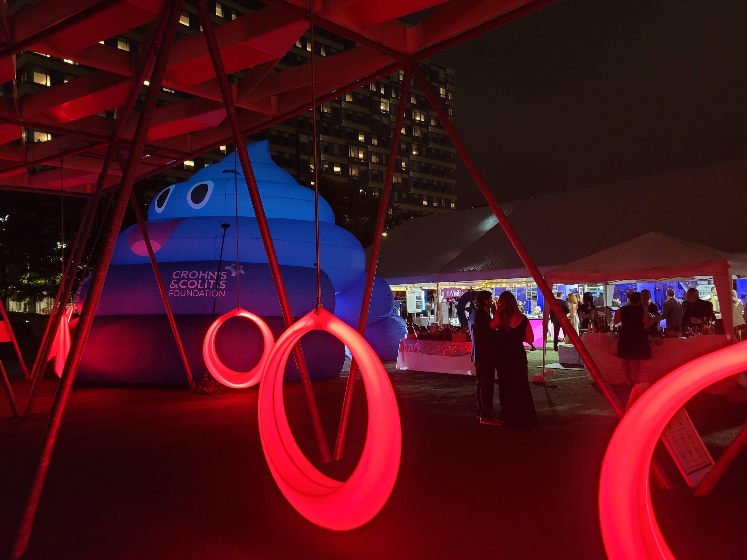 People surrounding blue and white tents with some ring-like red lights