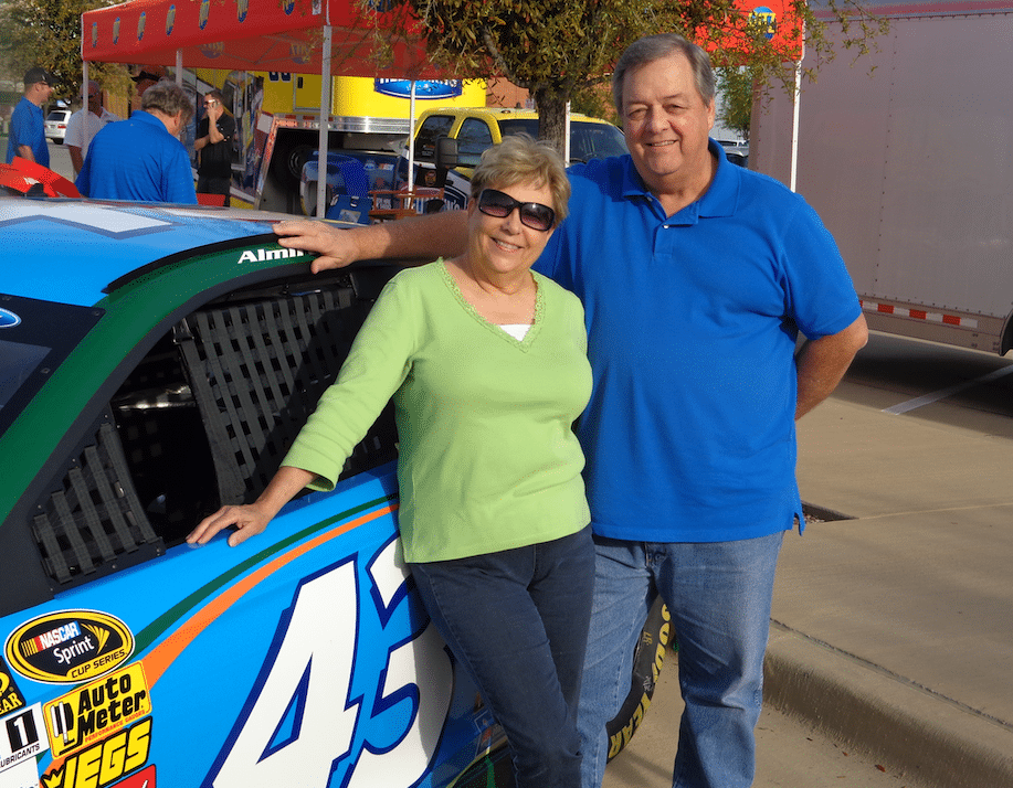 Two people posing with a car