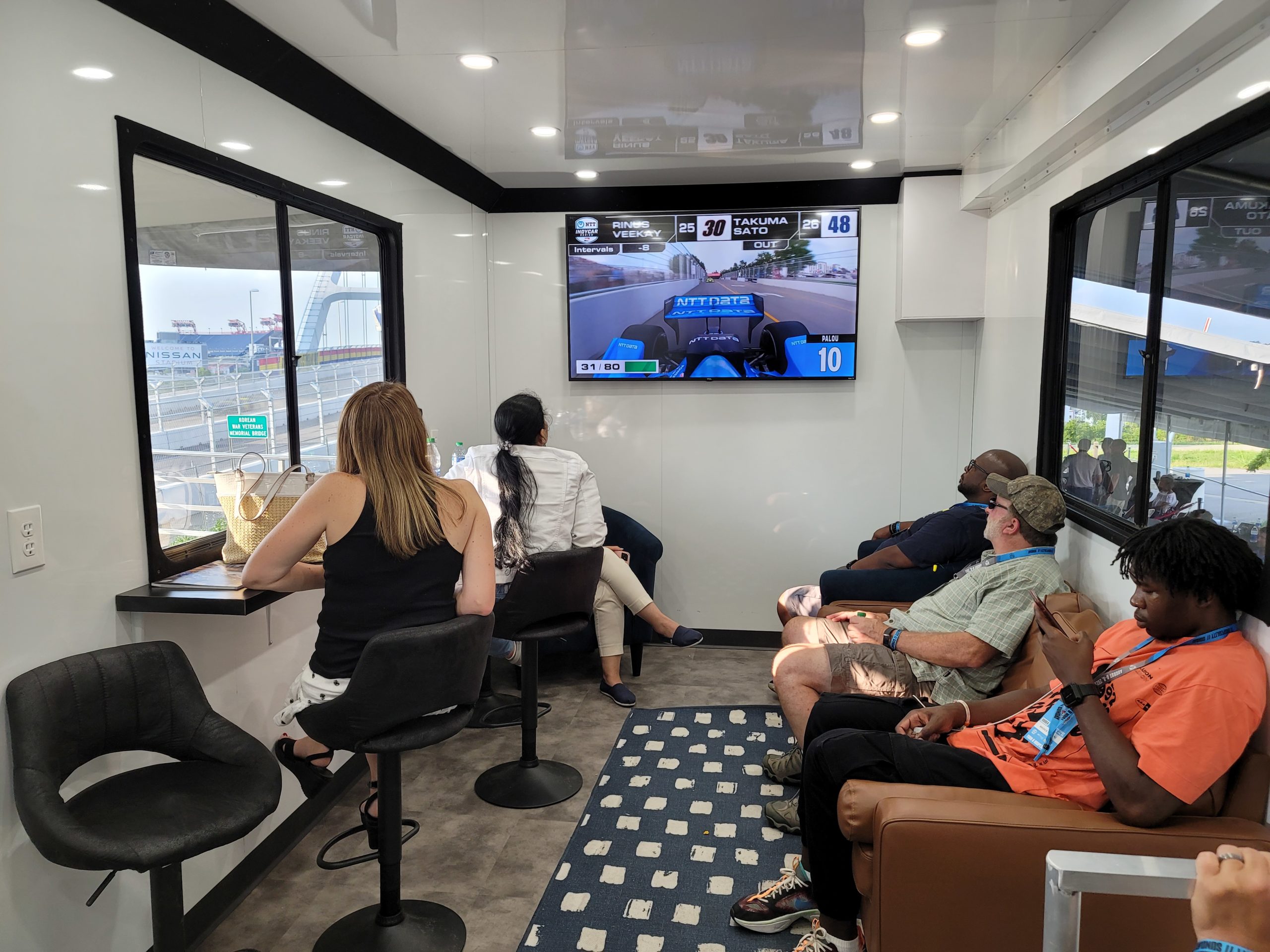 Interior of trailer at Music City Grand Prix with people sitting and watching TV