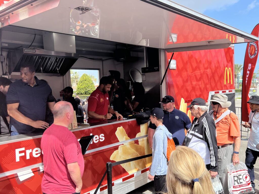 A crowd lining up in front of a Mc Donalds food truck by BMG