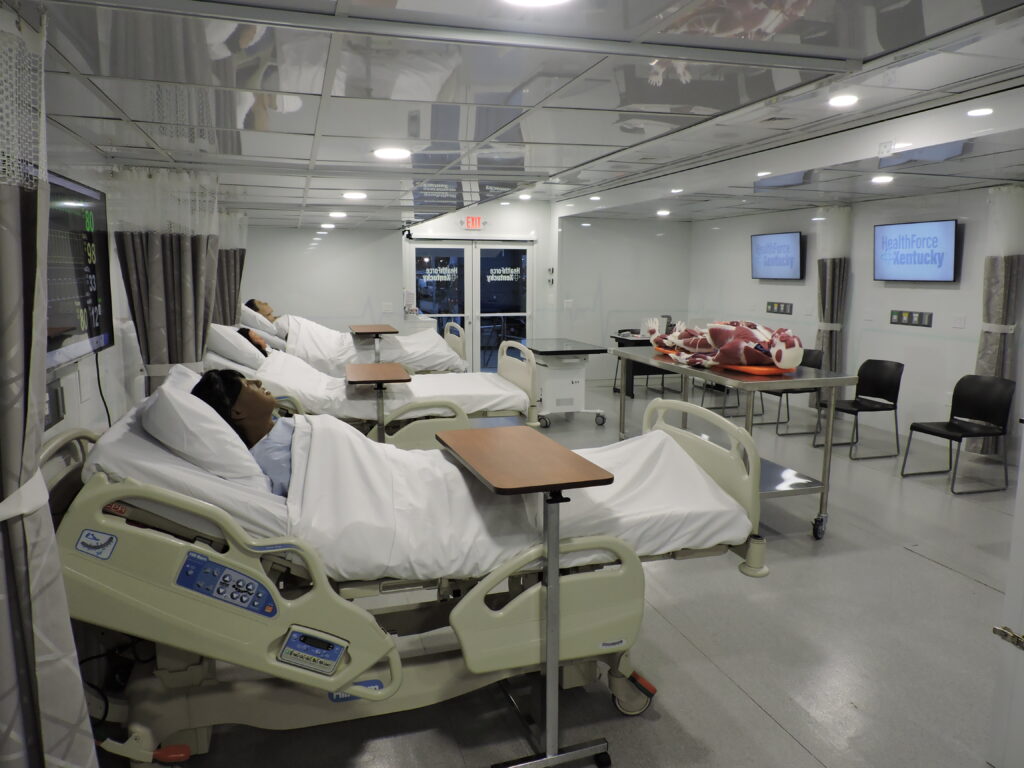 A hospital room with multiple beds and a television. Part of the Mobile Healthcare Units: The Post-Pandemic Healthcare Revolution.